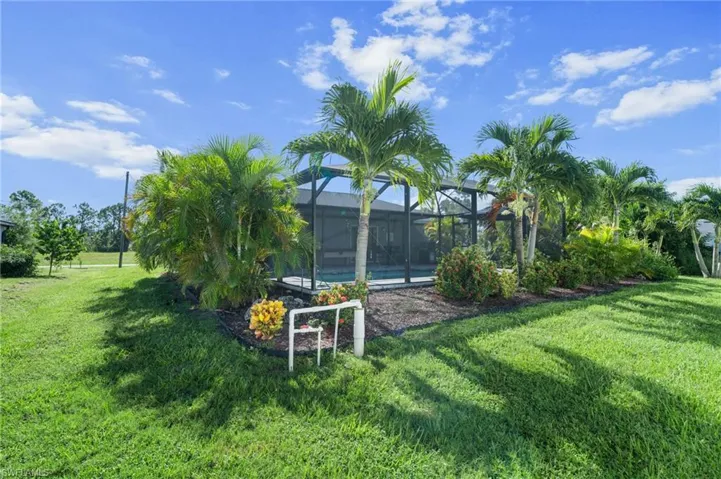 View of grassy yard with a sunroom and a lanai