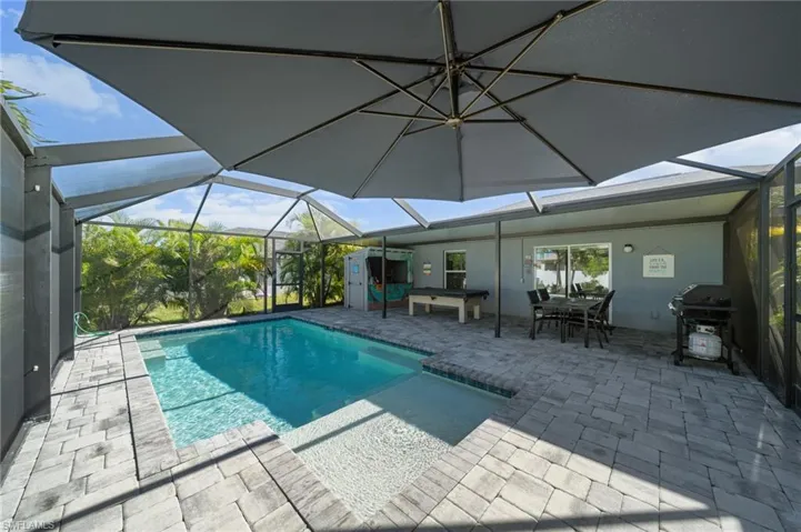 Swimming pool featuring a sunroom, a patio area, glass enclosure, and a grill