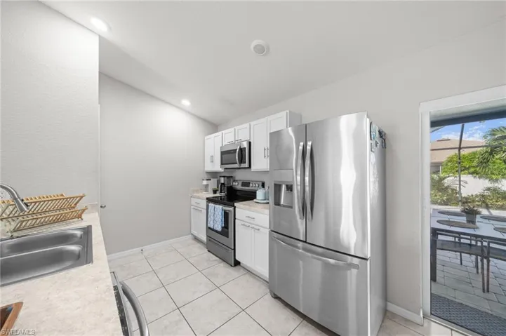 Kitchen with appliances with stainless steel finishes, light countertops, white cabinetry, light tile patterned floors, and recessed lighting