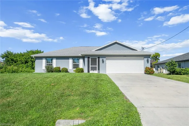 Ranch-style house featuring stucco siding, a front lawn, concrete driveway, and a garage