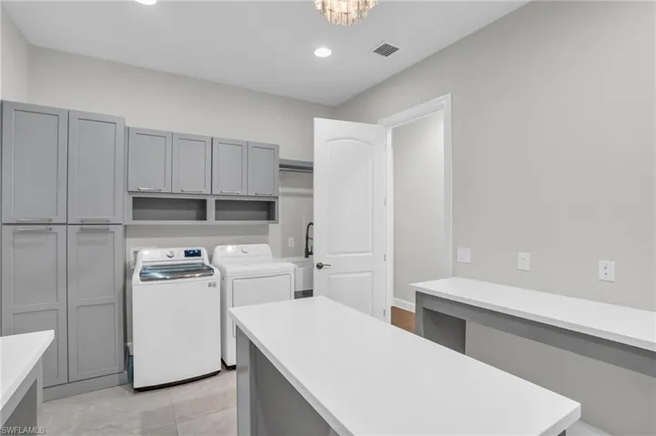 Washroom with cabinets, independent washer and dryer, utility sink, and light tile floors