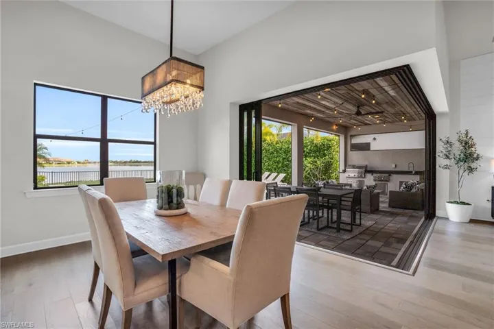 Dining space with a notable chandelier, hardwood floors, plenty of natural light, and a towering ceiling