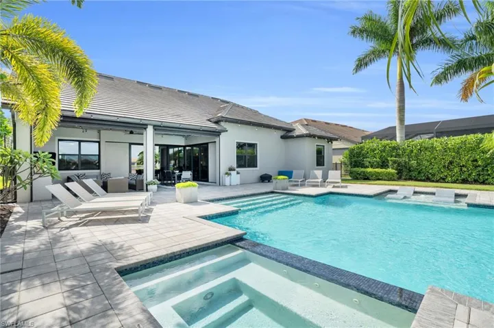 View of pool with a patio and an in ground hot tub