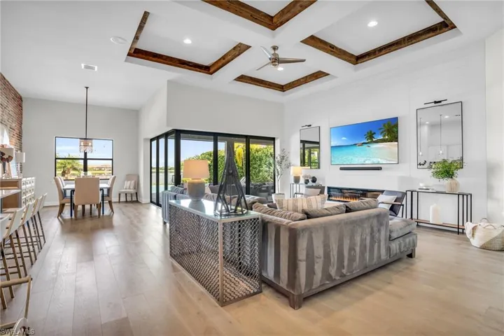 Living room with plenty of natural light, coffered ceiling, light hardwood flooring, and ceiling fan