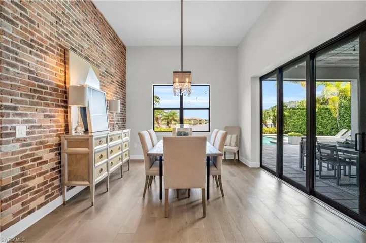 Dining area with brick wall, hardwood flooring, and a chandelier