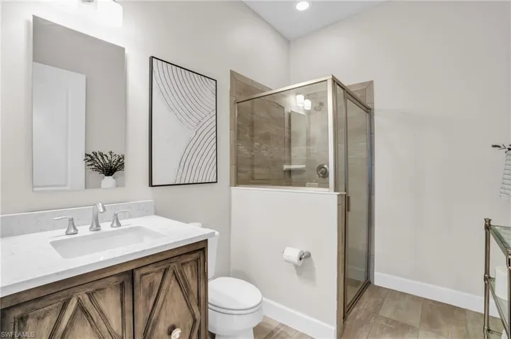 Bathroom 3 featuring a shower with door, hardwood floors, toilet, and custom vanity with extensive cabinet space