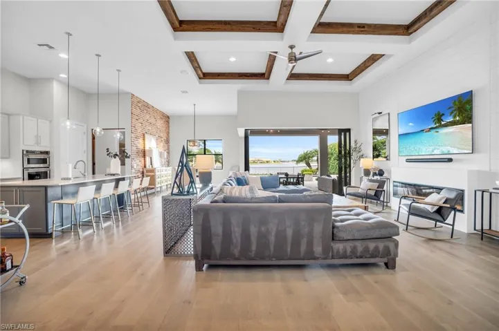 Living room featuring ceiling fan, light hardwood flooring, a high ceiling, coffered ceiling