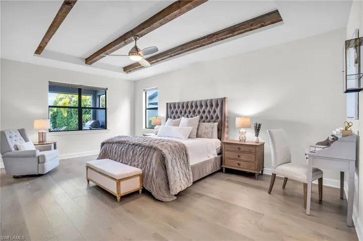 Bedroom featuring beam  tray ceiling, hardwood floors, and a ceiling fan