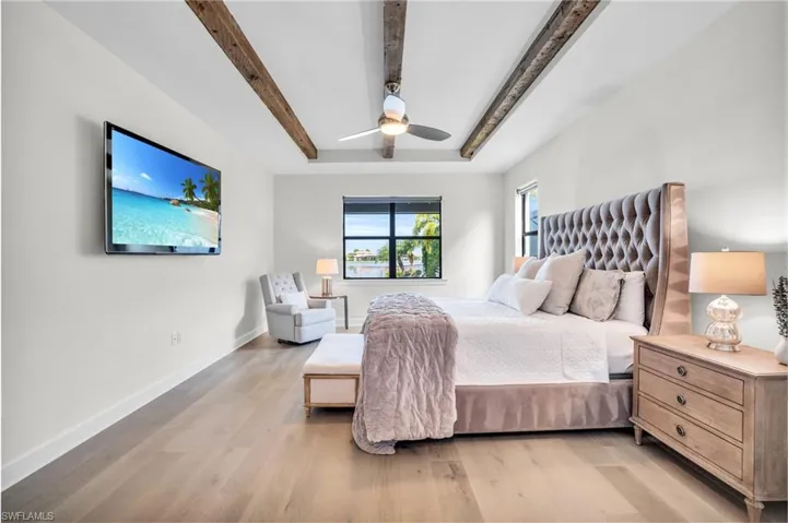 Bedroom featuring beam  tray ceiling, hardwood floors, and a ceiling fan