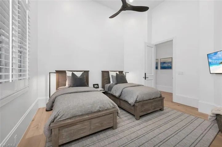 Bedroom featuring light hardwood / wood-style floors, ceiling fan, and a high ceiling