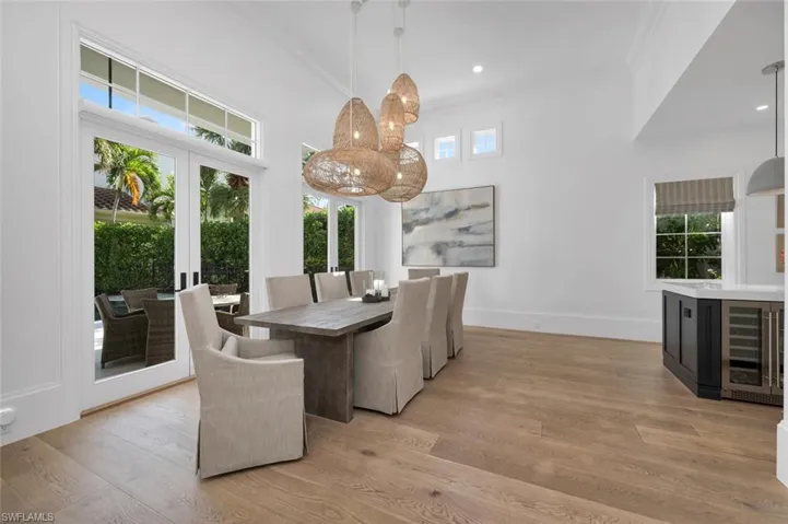 Dining room featuring wine cooler, french doors, crown molding, and light hardwood / wood-style flooring