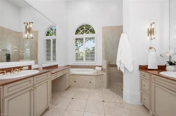 Bathroom with a towering ceiling, shower with separate bathtub, vanity, and tile patterned floors
