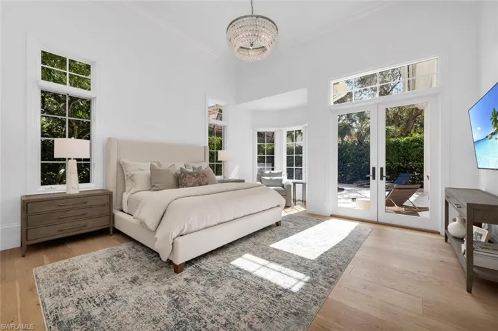 Bedroom with a towering ceiling, french doors, light hardwood / wood-style flooring, and access to outside