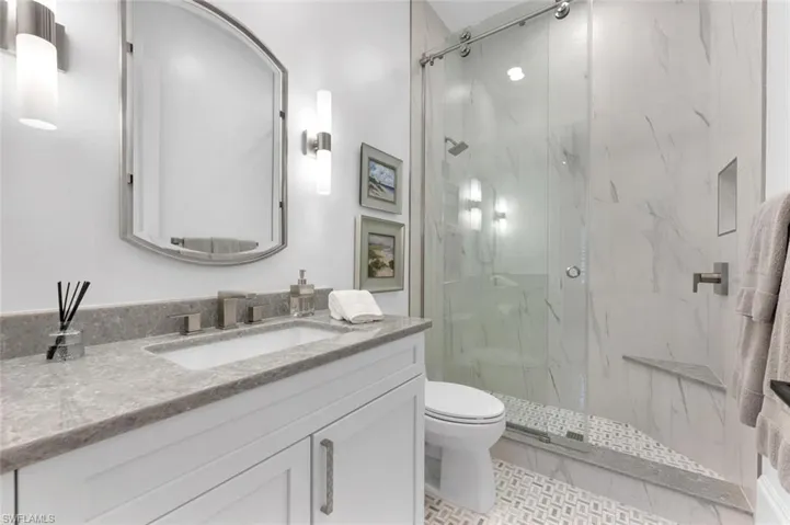 Bathroom with toilet, vanity, tile patterned flooring, and a shower with door