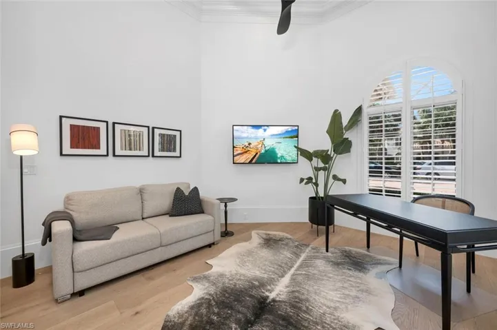 Office with light hardwood / wood-style flooring, ceiling fan, and crown molding