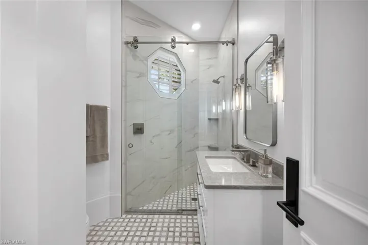 Bathroom featuring tile patterned floors, vanity, and a shower with door