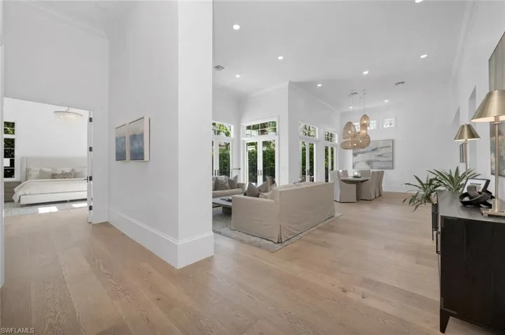 Hallway featuring an inviting chandelier, a high ceiling, light wood-type flooring, and crown molding