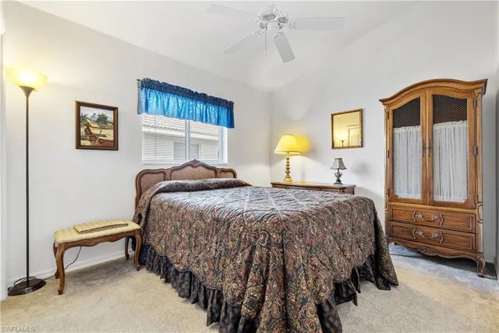 Bedroom featuring light carpet, vaulted ceiling, ceiling fan, and baseboards