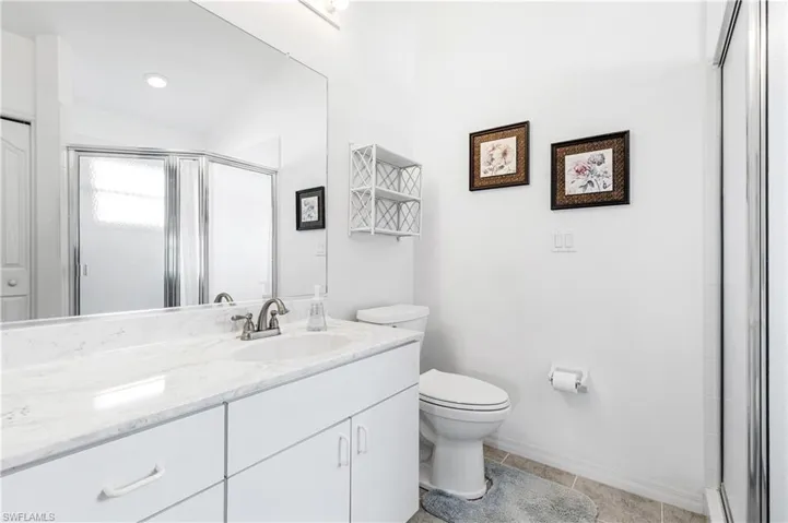 Full bathroom with vanity, toilet, a stall shower, vaulted ceiling, and tile patterned floors