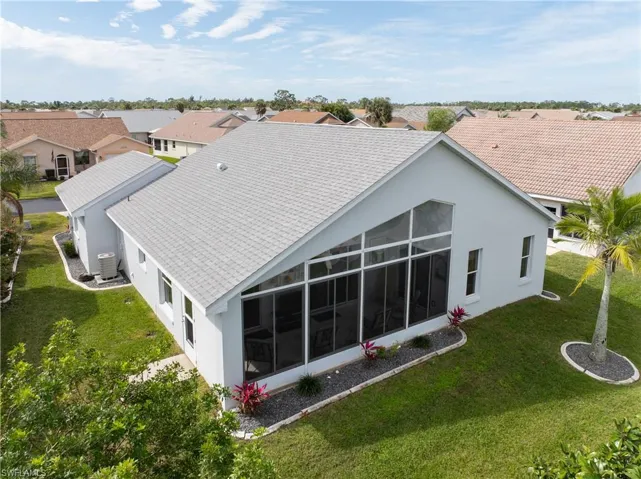 Back of property featuring stucco siding, a sunroom, a yard, and a residential view