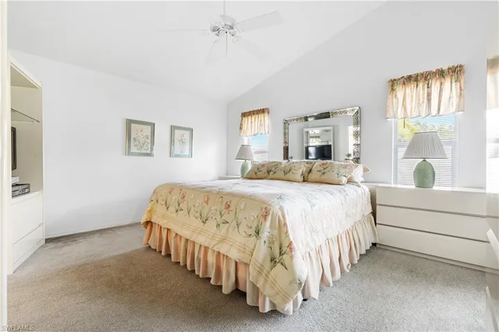 Bedroom featuring light carpet, a ceiling fan, and high vaulted ceiling