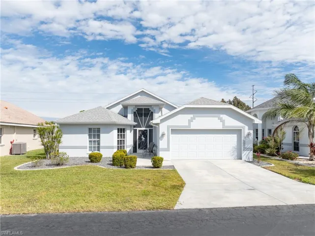 Ranch-style house with cooling unit, an attached garage, a front lawn, driveway, and stucco siding