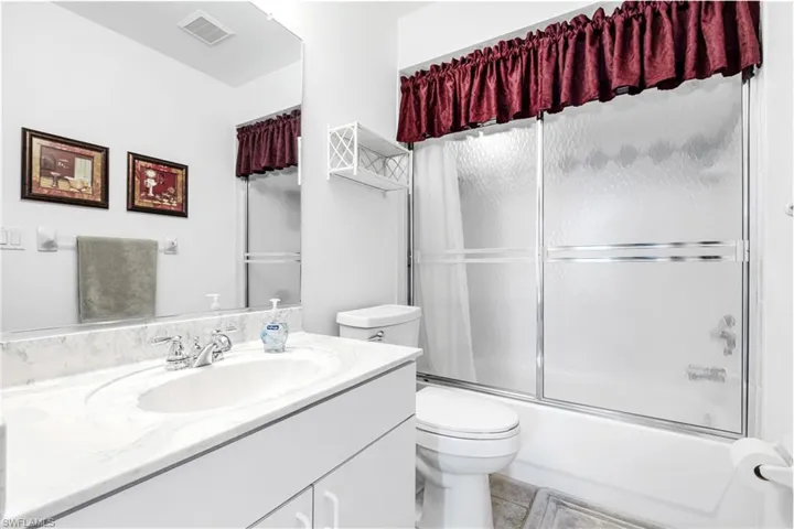 Full bath featuring toilet, vanity, combined bath / shower with glass door, and tile patterned floors