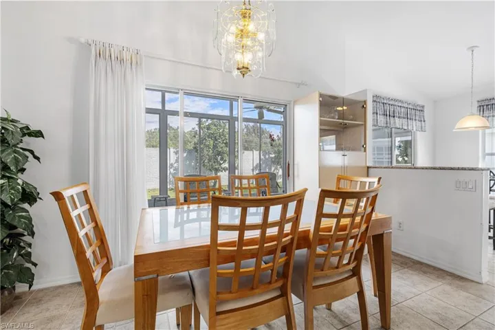 Tiled dining room featuring a chandelier and high vaulted ceiling