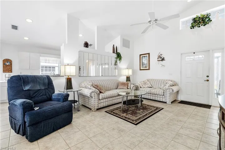 Living area featuring light tile patterned floors, high vaulted ceiling, ceiling fan, and recessed lighting