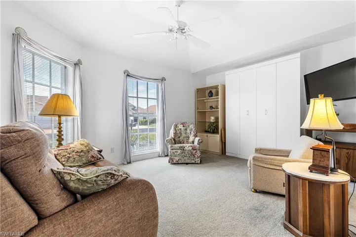 Living area featuring light colored carpet and ceiling fan