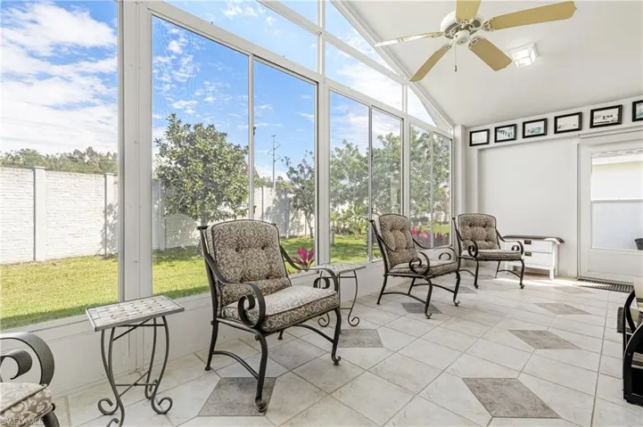 Sunroom with a ceiling fan, tile patterned floors, and lofted ceiling