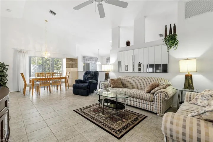 Living area with high vaulted ceiling, ceiling fan, and light tile patterned floors
