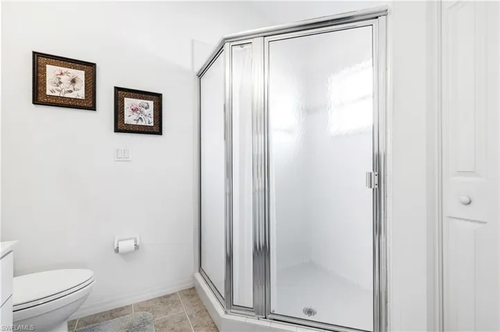 Bathroom with a stall shower, toilet, baseboards, tile patterned floors, and vanity