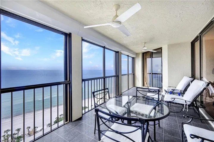 Sunroom featuring a water view, a textured ceiling, granite floors, a textured wall, and plenty of natural light