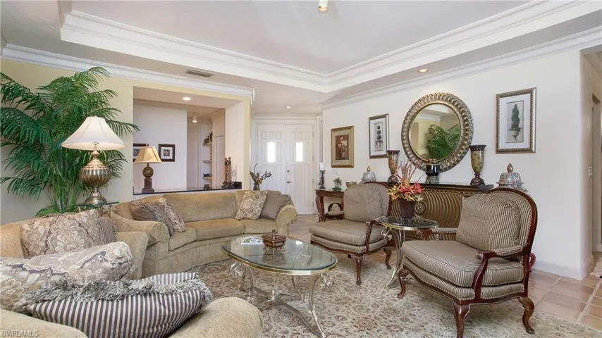 Tiled living room featuring a raised ceiling and ornamental molding