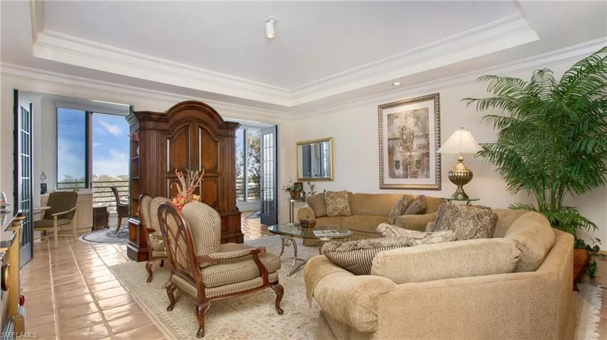 Living room with ornamental molding, a healthy amount of sunlight, and a raised ceiling