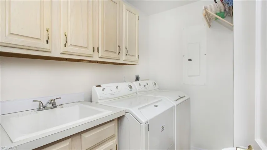 Laundry room featuring cabinets, electric panel, washer and clothes dryer, and sink