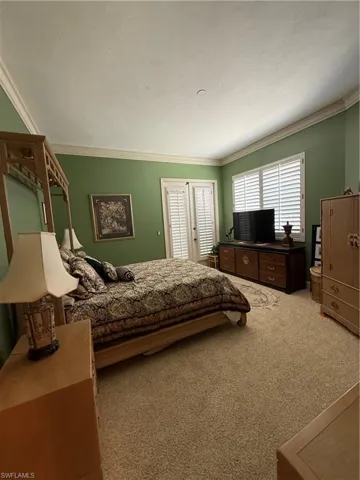 Bedroom with light colored carpet and ornamental molding