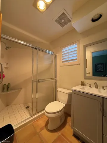 Bathroom featuring walk in shower, vanity, and toilet