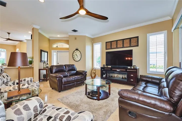 Living area featuring crown molding, ceiling fan, recessed lighting, and decorative columns