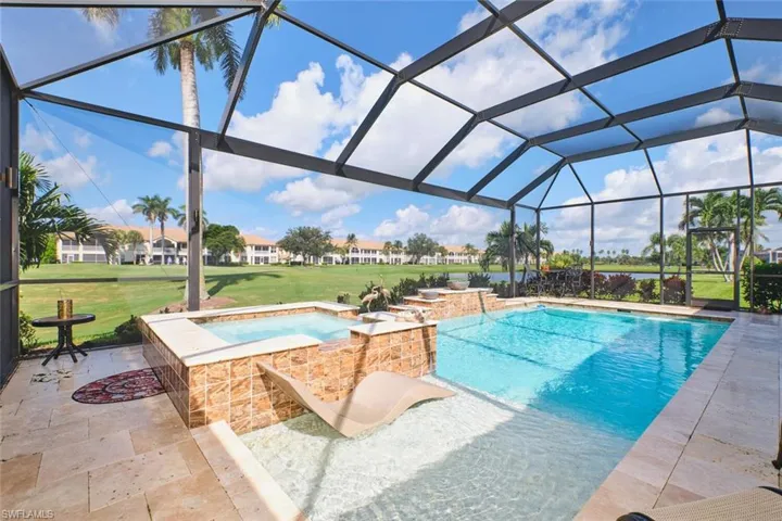 View of pool with a sunroom, a pool with connected hot tub, a yard, and glass enclosure