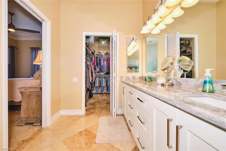 Full bathroom featuring double vanity, ornamental molding, a walk in closet, and ceiling fan