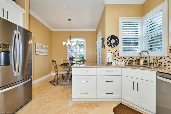 Kitchen with stainless steel appliances, white cabinets, crown molding, tasteful backsplash, and a chandelier