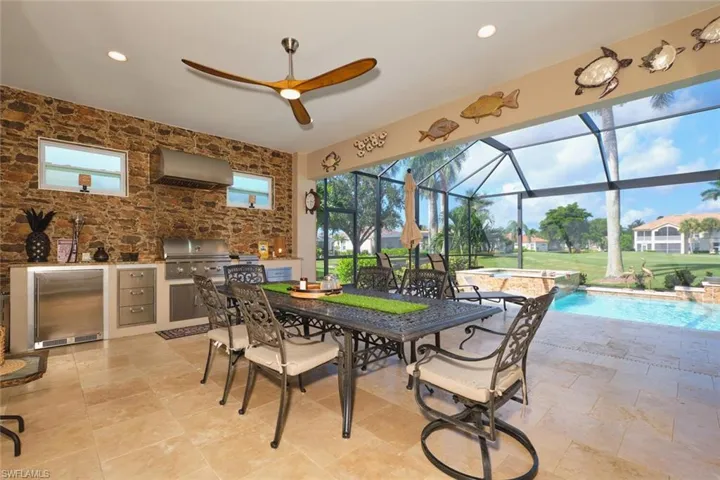 View of patio / terrace featuring an outdoor kitchen, a sunroom, glass enclosure, outdoor dining area, and a pool with connected hot tub