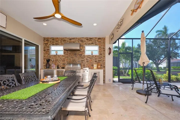View of patio featuring an outdoor kitchen, a sunroom, glass enclosure, outdoor dining area, and a ceiling fan