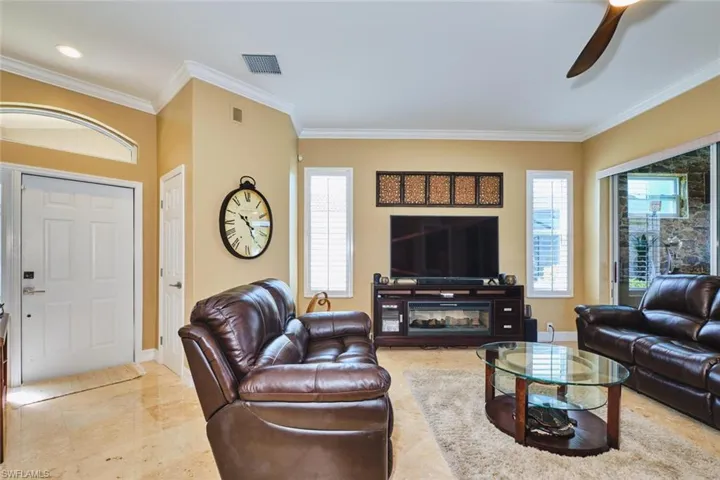 Living room with ornamental molding, healthy amount of natural light, and ceiling fan