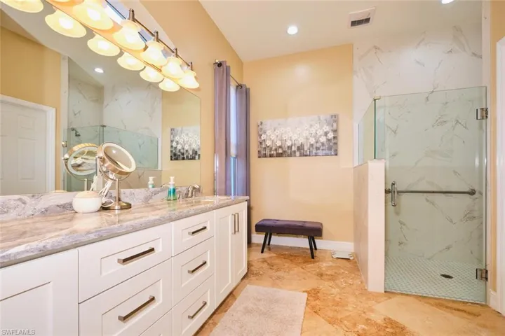 Bathroom with a marble finish shower, vanity, and recessed lighting