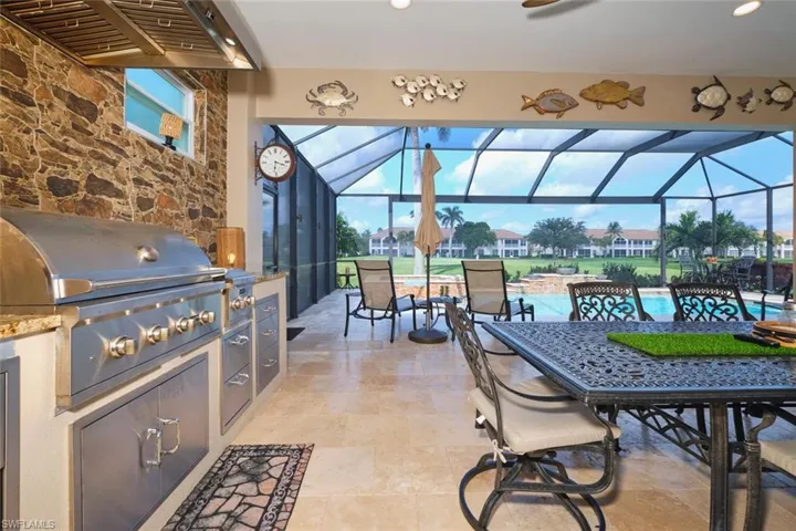 View of patio with exterior kitchen, a sunroom, an outdoor pool, glass enclosure, and outdoor dining space