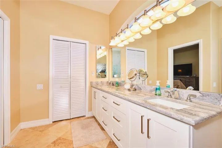 Bathroom featuring a closet, double vanity, and light tile patterned floors