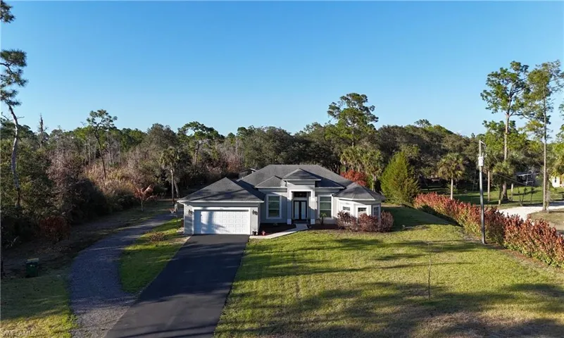 View of front of property with a front yard, a garage, and driveway